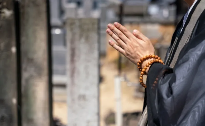 数珠を持ち合掌するお坊さんの写真